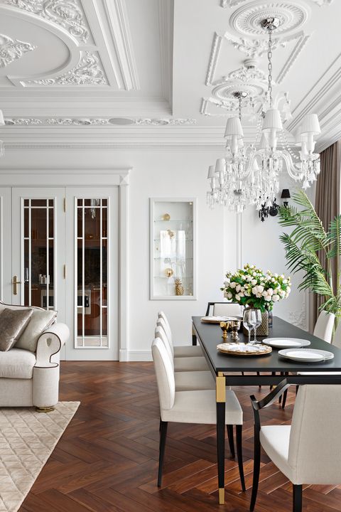 a refined living and dining room with a beautiful ceiling, dark-stained herringbone floors, a black table and white chairs