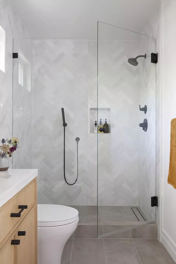 a small bathroom with marble herringbone tiles and grey ones on the floor, a stained vanity and black fixtures
