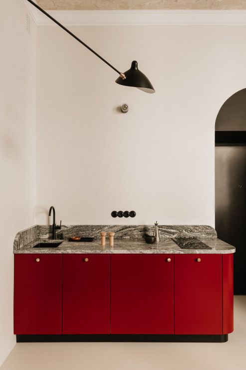 a small yet refined red kitchen with a grey stone countertop and black details is a lovely and bold solution