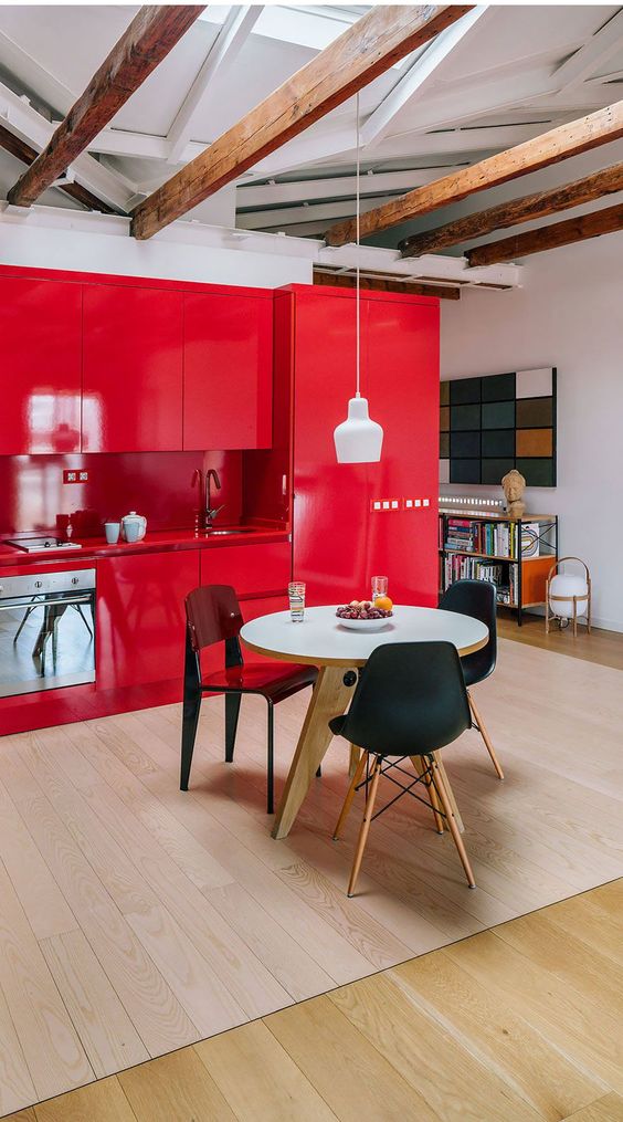 an extra bold red kitchen with matching countertops and a backsplash, a white round table and mismatching chairs