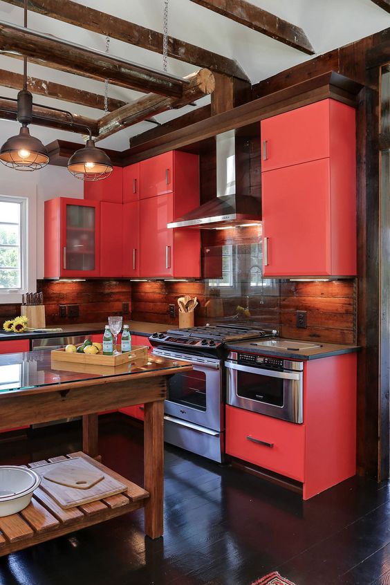 an extra bold red kitchen with stainless steel appliances, built-in lights and metal pendant lamps is a cool space