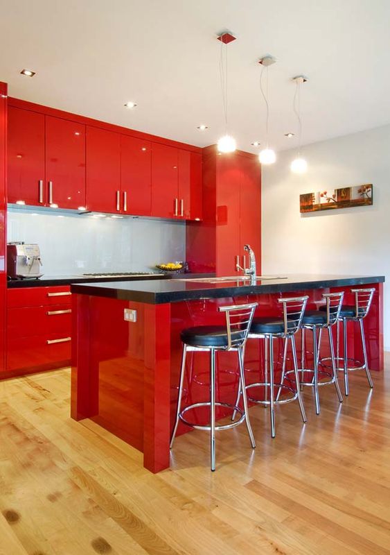 an extra bright red kitchen with black countertops, tall black stools and pendant lamps is a cool space