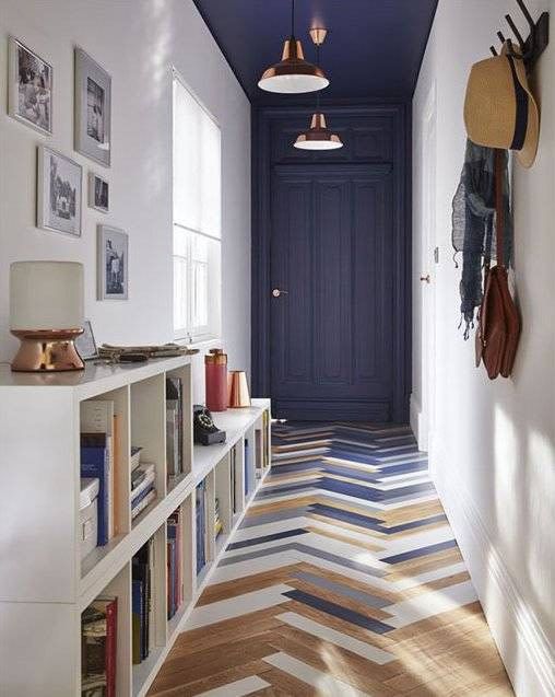 an eye-catchy entryway with a bold herringbone floor, a navy door and ceiling, a storage unit and a gallery wall