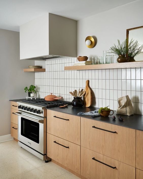 a chic modern meets Scandinavian kitchen with a white stacked tile backsplash, stained cabinets and black countertops