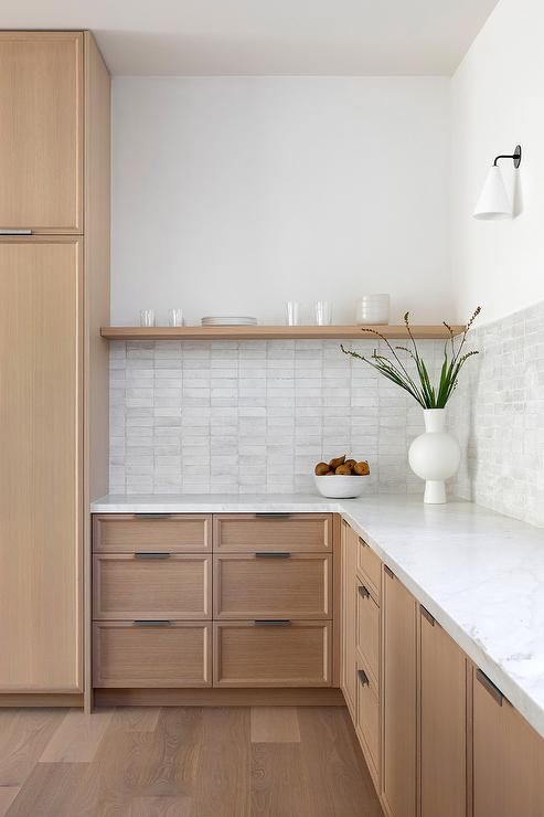 a light-stained oak kitchen with white countertops, an open shelf and a stacked tile backsplash is cool