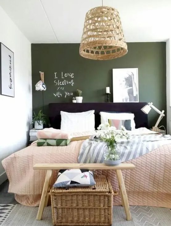 a lively bedroom with a green wall, a black bed, neutral and printed bedding, a bench, a woven chest and woven pendant lamp