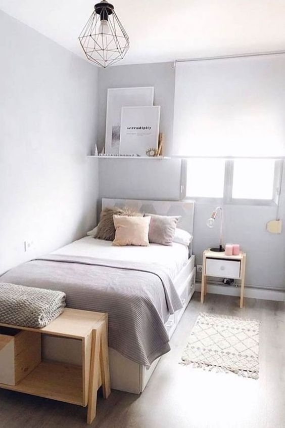 a narrow bedroom done in dove grey, with a bed and neutral bedding, a shelf ith decor, some nightstands