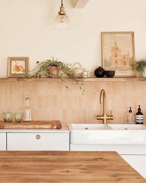 a neutral kitchen with white cabinets, a blush Zellige stacked tile backsplash, an open shelf and some decor
