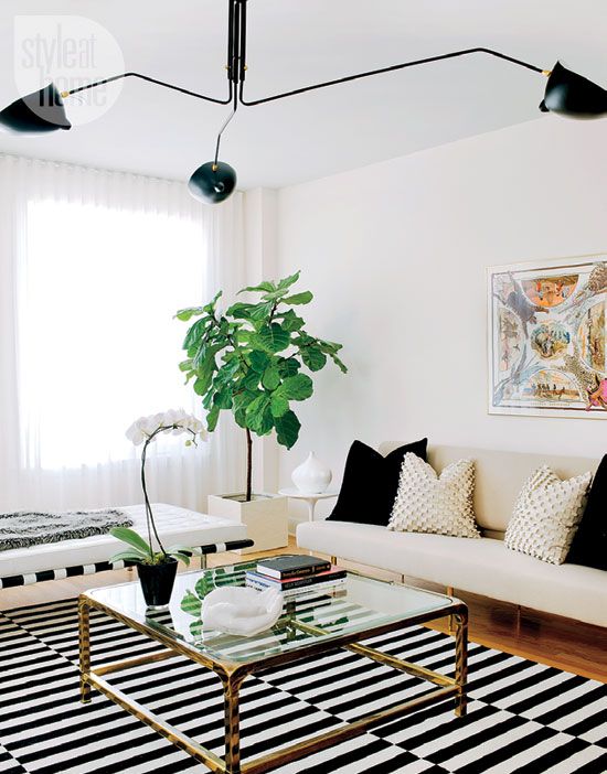 a-modern-black-and-white-lviing-room-with-a-striped-rug-a-neutral-sofa-with-black-and-gold-pillows-a-coffee-table-a-white-daybed-and-a-black-chandelier.jpg