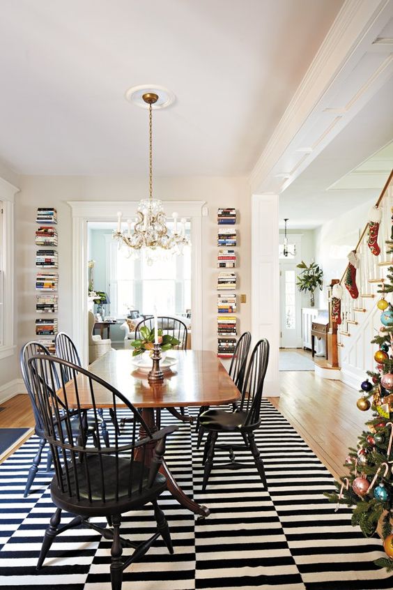 a-modern-dining-room-with-a-striped-rug-a-table-with-black-chairs-bookshelves-and-a-crystal-chandelier-is-very-welcoming.jpg