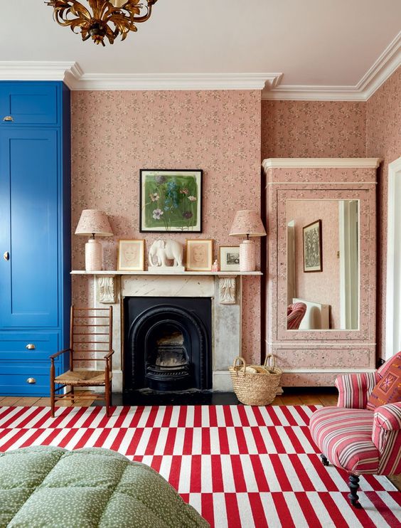 an-English-cottage-living-room-with-a-blue-wardrobe-a-fireplace-a-striped-rug-and-chair-pretty-pink-floral-wallpaper.jpg