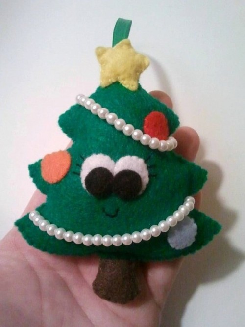 a green felt Christmas ornament shaped as a tree, with eyes, colorful ornaments and beads is a fun and whimsy item