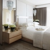 an oversized headboard plus upholstered panels over it plus mirrors on both sides of the bed make the bedroom larger and fresher