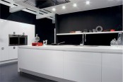 a contemporary black and white kitchen with black walls, sleek white cabinets and a kitchen island, built-in appliances and lights all over