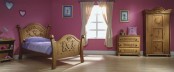 a mauve Princess themed kid’s room with carved wooden furniture and touches of blue