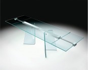 a glass dining table with glass legs and a metal construction that helps to hold the tabletop
