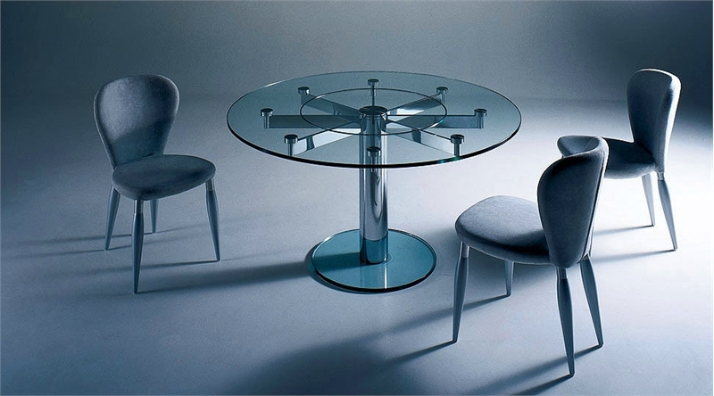 a modern dining table with a clear glass tabletop and a metal base plus a metal construction that holds the tabletop in place