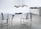 a contemporary dining room with a glass dining table with catchy metal legs and white and stainless steel chairs
