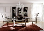 a lovely dining table of a creative base and a glass tabletop, vintage white chairs, a crystal chandelier and a large cupboard with catchy artwork
