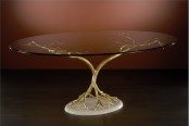 an oval glass tabletop is supported with gold branches on a stand is a lovely idea for a unique space with a quirky touch