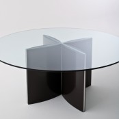 a modern dining table with a round tabletop and a black metal base of four petals looks eye-catchy and lightweight, the base is accented
