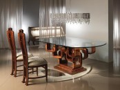 a sophisticated dining table with an oval glass tabletop and a refined and catchy wooden base, a unique crystal chandelie rand bold refined chairs
