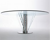 a modern dining table with round glass tabletop and a metal leg plus additional glass petals that hold the tabletop