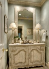 a grey Provence bathroom with shabby chic furniture, a chic shabby vanity, matching lamps and a lovely mirror