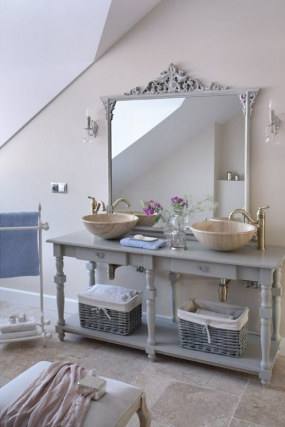 a neutral bathroom with a refined grey open vanity, bowl sinks and vintage faucets, a large mirror in a refined vintage frame plus various pastel towels