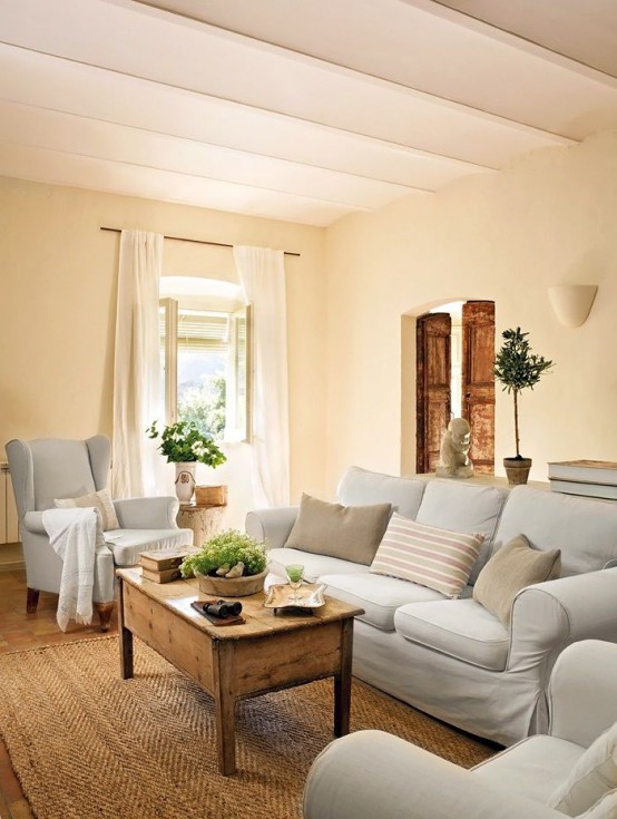 a farmhouse Provence living room with neutral furniture, a jute rug and a low coffee table of stained wood