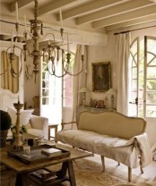 a neutral and chic Provence living room with refined furniture, a lovely chandelier, neutral blankets and pillows is beautiful