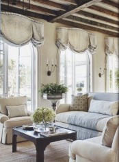 a vintage Provence living room in neutrals, with refined furniture, draped curtains, a low table and potted greenery