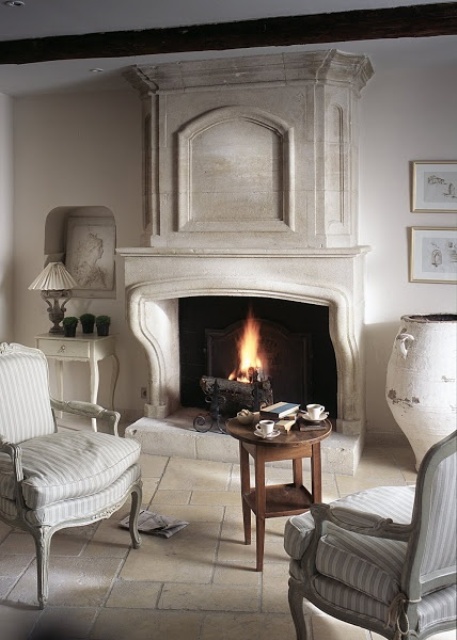 a neutral Provence living room with a refined fireplace, chic furniture, low tables and a gallery wall