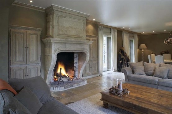 a refined neutral living room with whitewashed walls, a large fireplace, neutral sofas and a low table