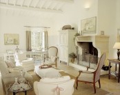 a chic neutral Provence living room with a large fireplace, refined furniture, curtains and potted plants