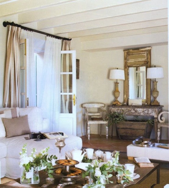 a neutral and beautiful Provence living room with a mirror, chic furniture, curtains, potted greenery and table lamps is wow