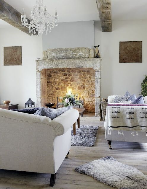 an exquisite Provence living room with a stone fireplace, refined furniture, a crystal chandelier and wooden beams, white and blue textiles