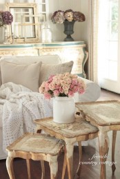 a neutral shabby chic Provence living room with a white sofa, a stack of refined stools and frames plus pastel blooms