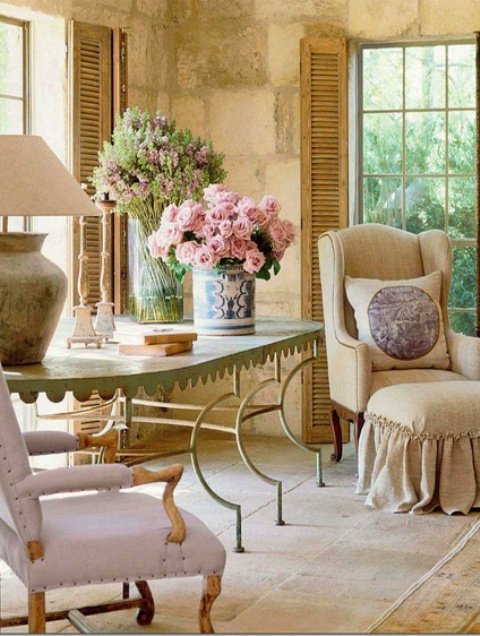 a neutral living room with stone walls, shutters, neutral refined furniture and beautiful floral arrangements is wow