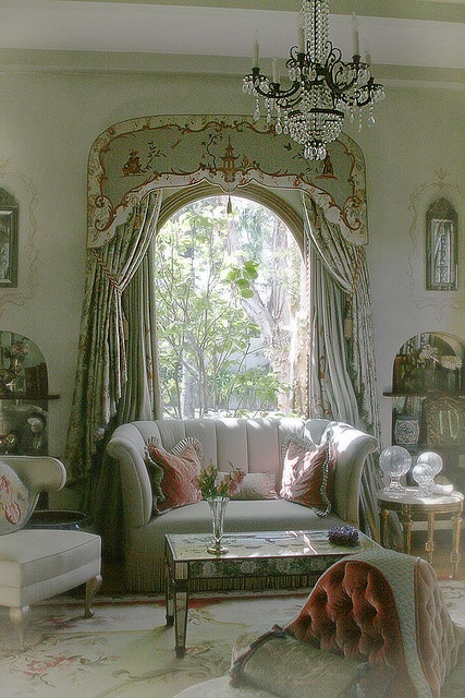 a green Provence living room with refined modern furniture, lovely floral curtains and a crystal chandelier plus a low table