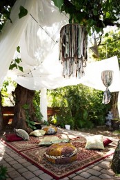 a soothing boho chic nook with Moroccan rugs and colorful pillows, white canopies and hanging tassel chandeliers