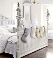 a neutral Christmas bedroom with cozy bedding, faux fur pillows and blankets and stockings and snowy evergreens