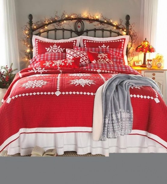 a Christmas bedroom with red and white bedding, a grey plaid blanket and lights covering the headboard