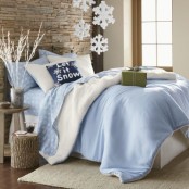 a neutral bedroom decorated with frosted lights in a vase, snowflke hangings and a blue bedding set inspired by Christmas