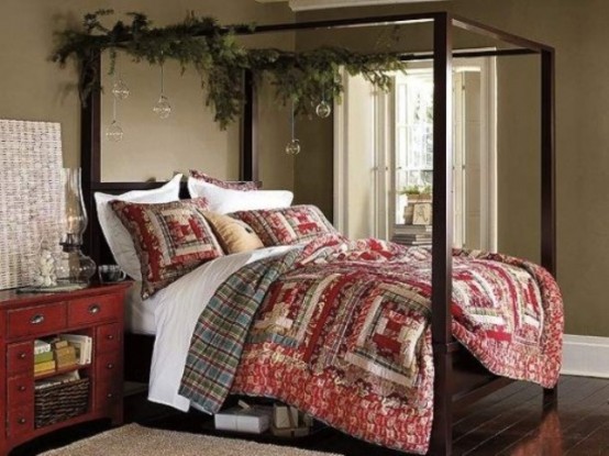a Christmas bedroom with bright quilted bedding, evergreens and clear bubble ornaments hanging on the bed frame