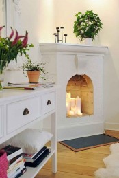 a simple and small white fireplace with pillar candles is a cool idea for a modern space