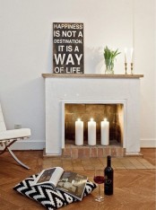a minimalist look with three large pillar candles and some candles on the mantel