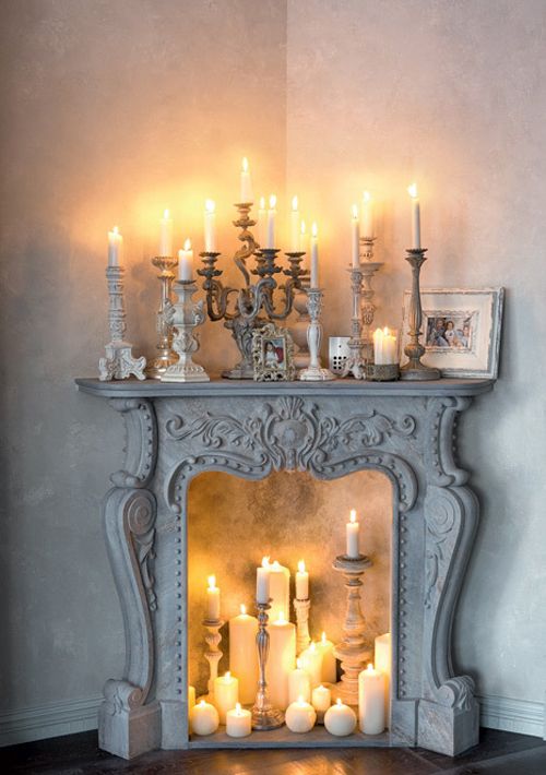 a refined vintage whitewashed fireplace with candles of various sizes and shapes, with vintage candle holders