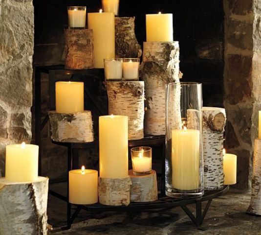 a stepped stand with pillar candles and wooden stumps as candle holders