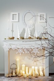 a chic winter fireplace with pillar candles, a candle lantern and snowflake buntings for the holidays